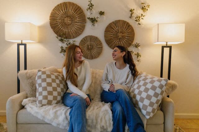 Two residents smile in a living room at The Colleges at La Rue.